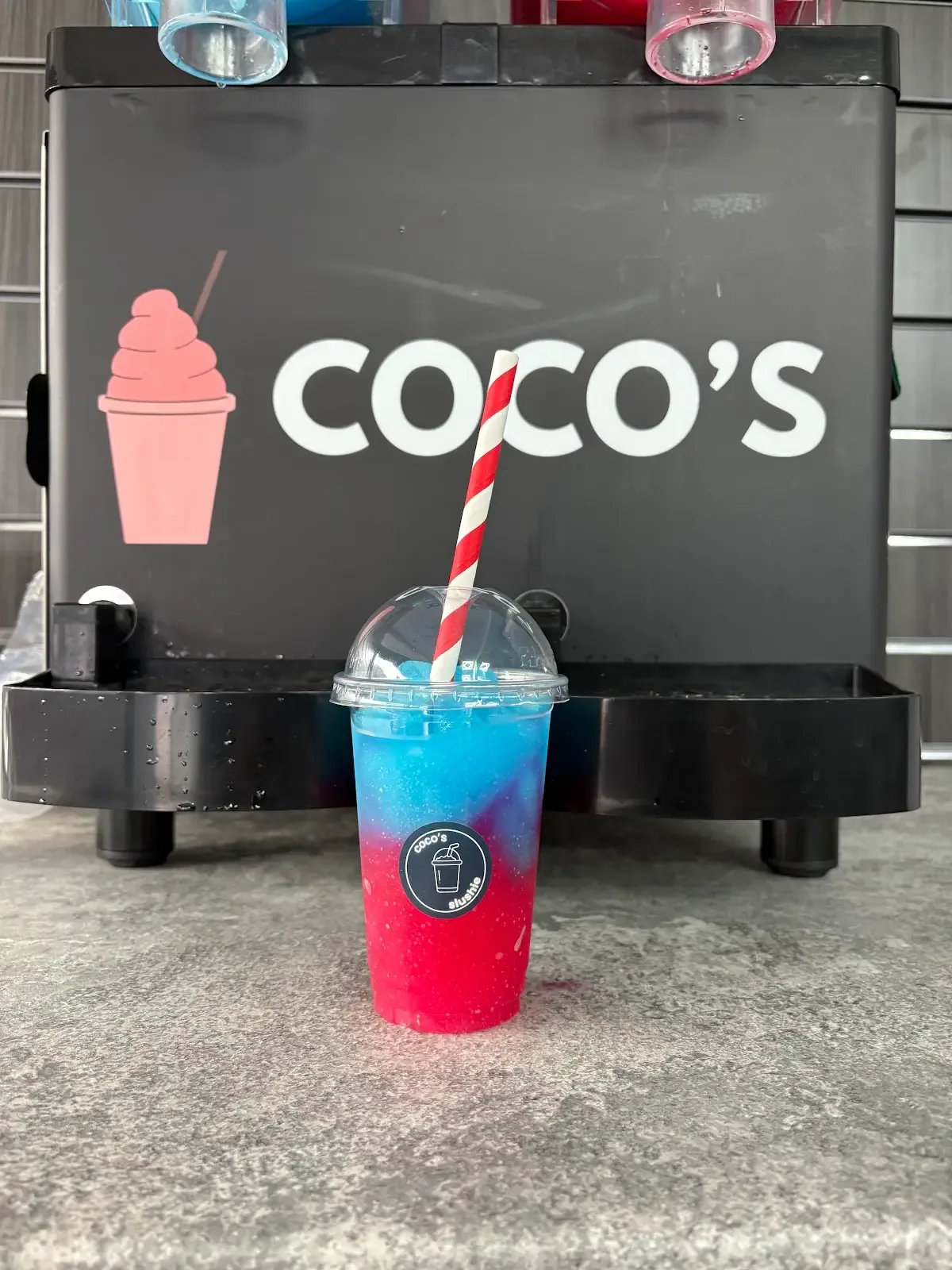 Coco’s red and blue slushie beside the machine